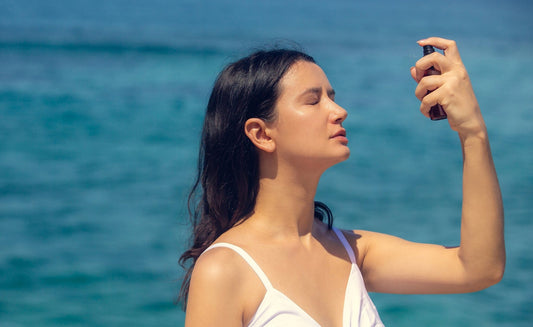 A woman sprays her face with a face toner. If you've ever wondered if toner comes before or after moisturizer, check out our guide for all the tips.