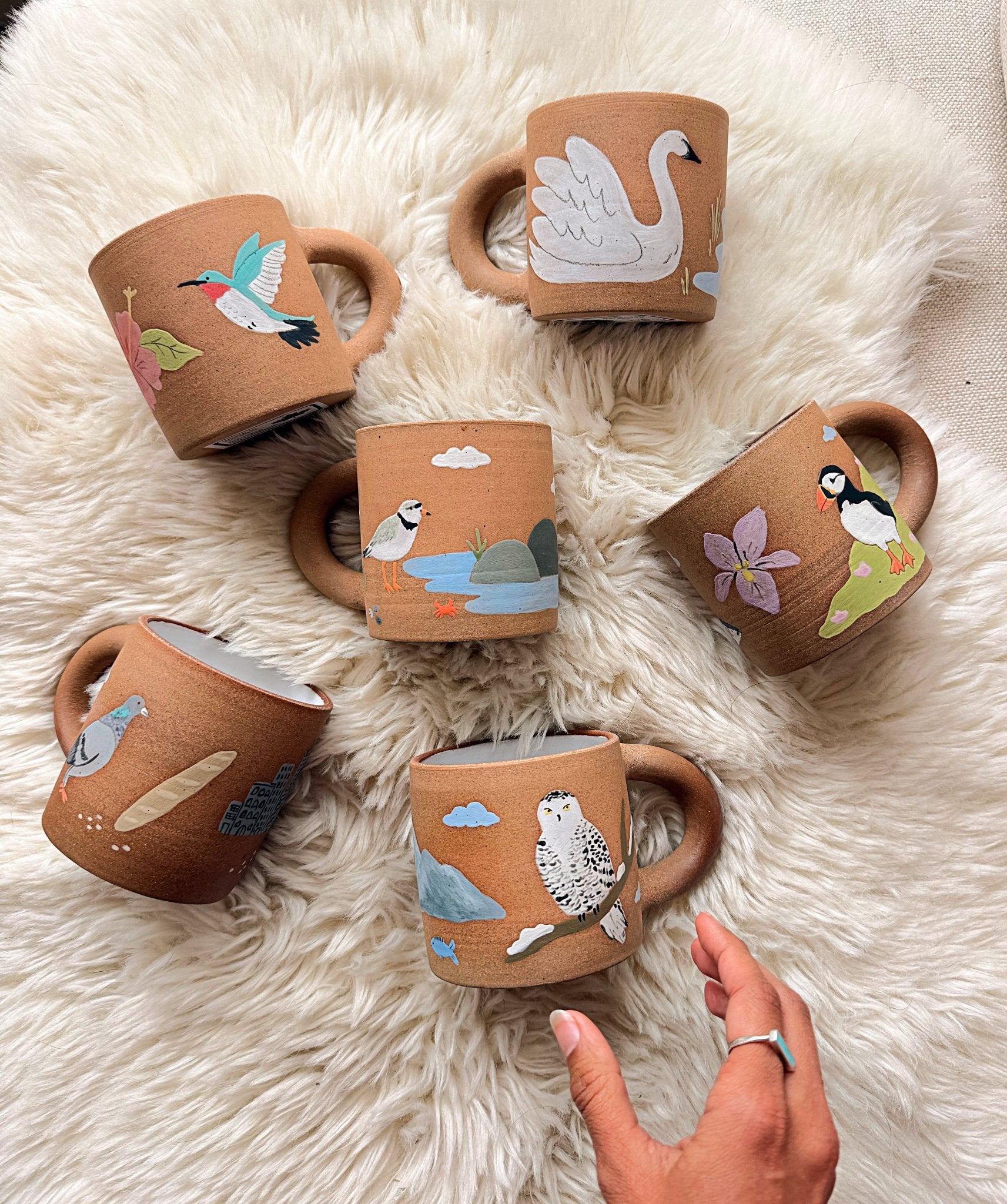 Set of ceramic mugs with animal illustrations on a fluffy white surface